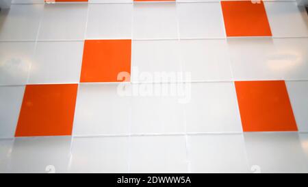 A white wall with an orange tile. Selective focus Stock Photo