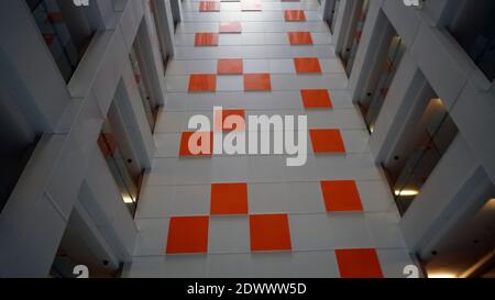 A white wall with an orange tile. Selective focus Stock Photo