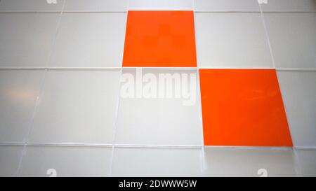A white wall with an orange tile. Selective focus Stock Photo