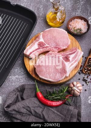 fresh raw pieces meat pork, beef, chop on a bone on the board, spices, grill pan Stock Photo