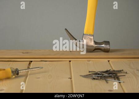 Pull out the nail with a claw hammer. The hammer is removing the nail from the wooden board. Hammer nail puller pull big nail out of the board. Small Stock Photo