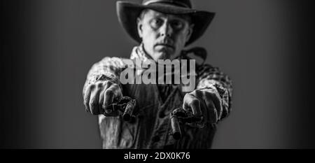 Man wearing cowboy hat, gun. West, guns. Portrait of a cowboy. Cowboy with weapon on background. Black and white Stock Photo