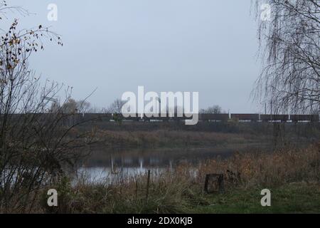 autumn landscape in cold tones lake and iron-roading distance with train trees. Stock Photo