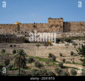 Jerusalem, Israel - December 17th, 2020: The sealed gate of mercy in the wall of old Jerusalem, with a muslim graveyard on its outer side, and the dom Stock Photo