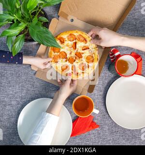 Small pizza pepperrone in a box on a set table, top view, family lunch. Stock Photo