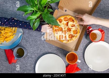 Small pizza pepperrone in a box on a set table, top view, family lunch. Stock Photo