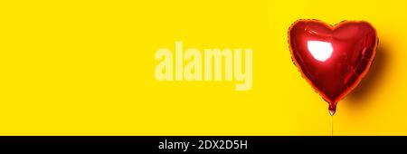 Air balloon in the form of a heart on a yellow background. Banner. Stock Photo