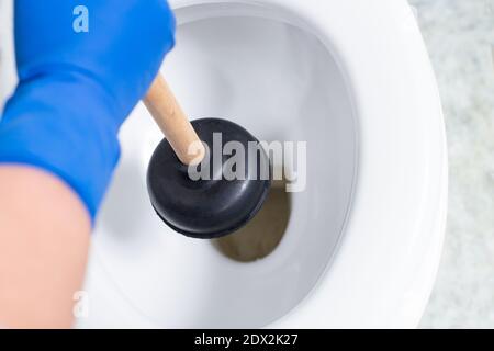 Hands using suction cup for cleaning stuck in toilet. Stock Photo
