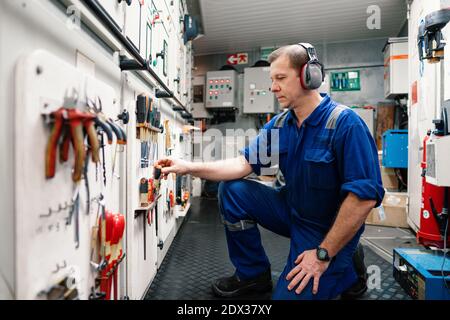 Marine engineer officer in engine control room ECR. He works in workshop Stock Photo