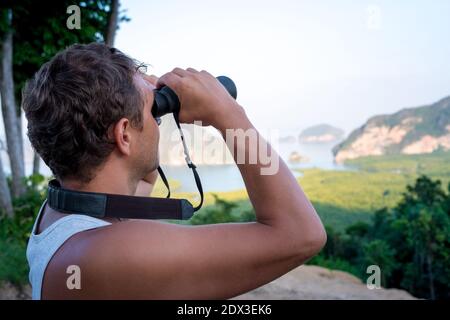 A man looks through binoculars on the sea rocks Stock Photo