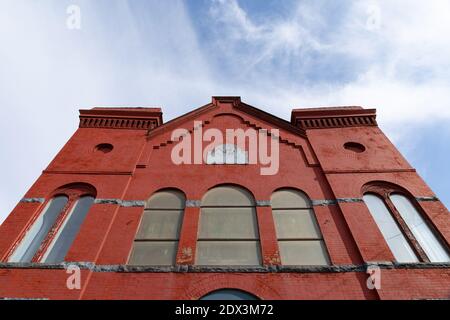 Straight on view looking up of an old red brick church with arched windows, blue sky copy space, horizontal aspect Stock Photo