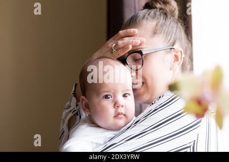 Childhood, motherhood, illness family concepts - upset, tired nervous business woman Lady mother with headache holding infant child newborn baby in Stock Photo