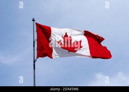 Flag of Canada on flagpole with blue sky in background Stock Photo