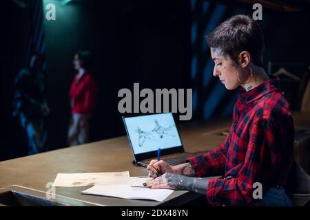 The administrator of a tattoo parlor draws a sketch of a tattoo using a laptop in the workshop Stock Photo