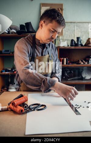 Hereditary tanner will be conducting a master class on making shoes from the skin, making a pattern on paper in his studio. Stock Photo