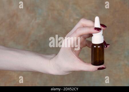 Female hand holding nasal spray pump in glass bottle Stock Photo