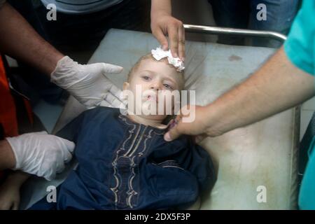 Palestinians gather around a boy, whom medics said was wounded by Israeli shelling near a market in Shejaia, at a hospital in Gaza City July 30, 2014. Israeli strikes near a market in the eastern Gaza Strip killed 15 Palestinians on Wednesday, the local health ministry said. Residents said that Israeli shelling and two missiles from the air hit the area in Shejaia, on the fringes of the city of Gaza. Ashraf al-Qidra, spokesman of the Gaza Health Ministry, said 160 people were also wounded. An Israeli military spokeswoman said she was checking the report. Israel launched its offensive in respon Stock Photo