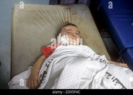 Palestinians gather around a boy, whom medics said was wounded by Israeli shelling near a market in Shejaia, at a hospital in Gaza City July 30, 2014. Israeli strikes near a market in the eastern Gaza Strip killed 15 Palestinians on Wednesday, the local health ministry said. Residents said that Israeli shelling and two missiles from the air hit the area in Shejaia, on the fringes of the city of Gaza. Ashraf al-Qidra, spokesman of the Gaza Health Ministry, said 160 people were also wounded. An Israeli military spokeswoman said she was checking the report. Israel launched its offensive in respon Stock Photo