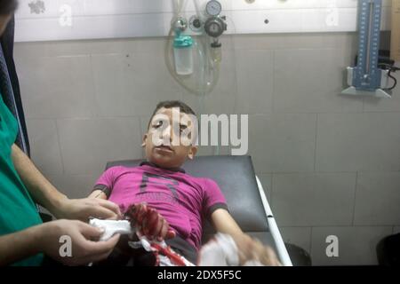 Palestinians gather around a boy, whom medics said was wounded by Israeli shelling near a market in Shejaia, at a hospital in Gaza City July 30, 2014. Israeli strikes near a market in the eastern Gaza Strip killed 15 Palestinians on Wednesday, the local health ministry said. Residents said that Israeli shelling and two missiles from the air hit the area in Shejaia, on the fringes of the city of Gaza. Ashraf al-Qidra, spokesman of the Gaza Health Ministry, said 160 people were also wounded. An Israeli military spokeswoman said she was checking the report. Israel launched its offensive in respon Stock Photo