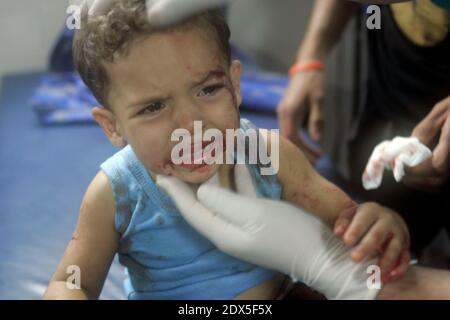 Palestinians gather around a boy, whom medics said was wounded by Israeli shelling near a market in Shejaia, at a hospital in Gaza City July 30, 2014. Israeli strikes near a market in the eastern Gaza Strip killed 15 Palestinians on Wednesday, the local health ministry said. Residents said that Israeli shelling and two missiles from the air hit the area in Shejaia, on the fringes of the city of Gaza. Ashraf al-Qidra, spokesman of the Gaza Health Ministry, said 160 people were also wounded. An Israeli military spokeswoman said she was checking the report. Israel launched its offensive in respon Stock Photo