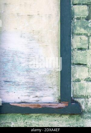 Close-up of a blank pale green poster surface at upper left, in a dark green wooden frame on a pale green brick wall. Stock Photo