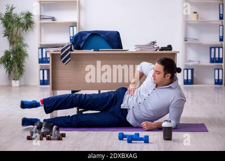 Handsome male employee doing exercises in the office Stock Photo