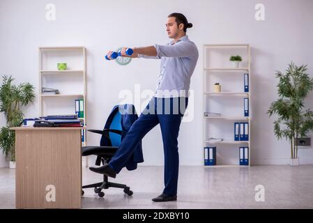 Handsome male employee doing exercises in the office Stock Photo