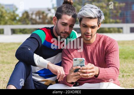 Man with gay partner using mobile phone in park Stock Photo