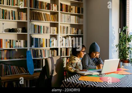 Boys e-learning through laptop with concentration while sitting in living room Stock Photo