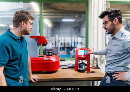 Businessman explaining about surveyor machine to male colleague at industry Stock Photo