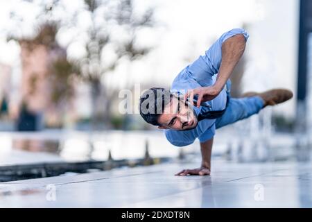 Businessman talking on mobile phone while doing handstand on footpath Stock Photo