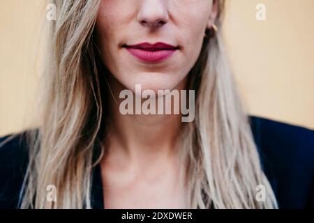 Close-up of woman wearing pink lipstick against yellow wall Stock Photo