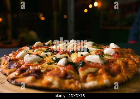 top view Traditional italian pizza with green basil pesto sauce on a black rustic wooden background.restaurant blur background Stock Photo