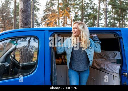 Happy woman day dreaming while leaning out of van door Stock Photo