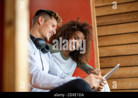 Smiling young couple using digital tablet while sitting at home Stock Photo