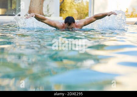 Young man doing butterfly stroke in swimming pool Stock Photo