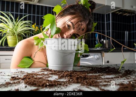 Woman leaning on flower pot at home Stock Photo