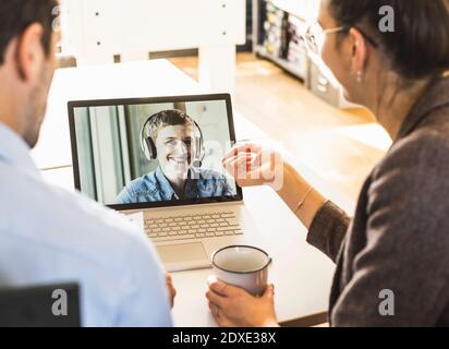 Team having meeting over video conference on laptop at office Stock Photo