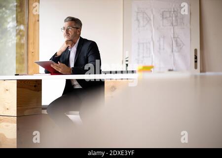 Thoughtful businessman using digital tablet while sitting at home Stock Photo