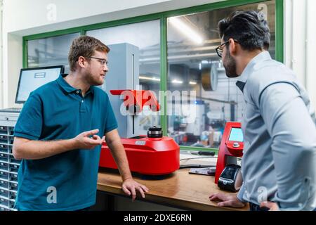 Male worker explaining surveyor machine to businessman at industry Stock Photo