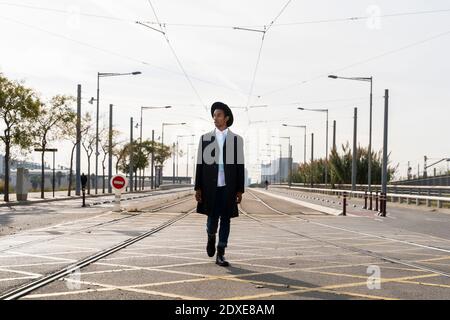Fashionable young man walking between railroad track on street Stock Photo