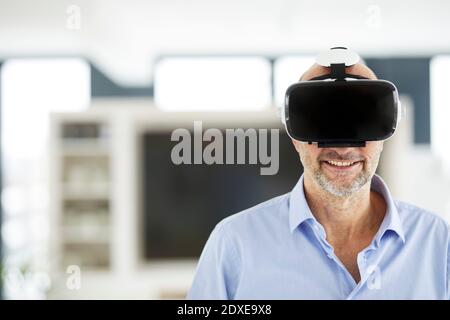 Businessman using virtual reality headset while standing at home Stock Photo