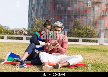 Smiling man with gay partner using mobile phone in park Stock Photo