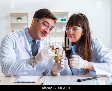 The two archeologists looking at ancient gold lamp Stock Photo