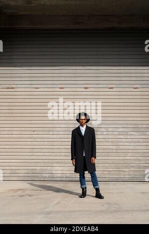 Fashionable young man standing against shutter on sunny day Stock Photo