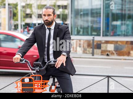 Portrait of bearded businessman sitting on bicycle Stock Photo