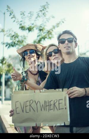 Young friends anticipating while holding placard written with text on footpath Stock Photo