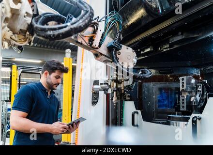 Young male worker using digital tablet while standing at manufacturing industry Stock Photo