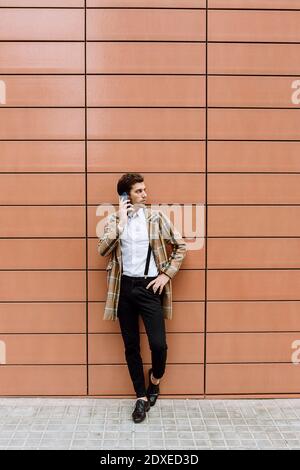 Stylish young man with smart phone standing at building Stock Photo