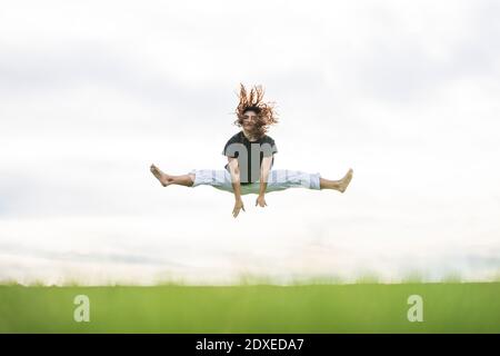 Carefree young athlete doing splits against sky Stock Photo